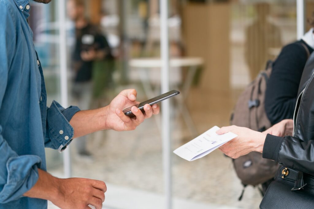 man holding smartphone in front of person in black leather jacket